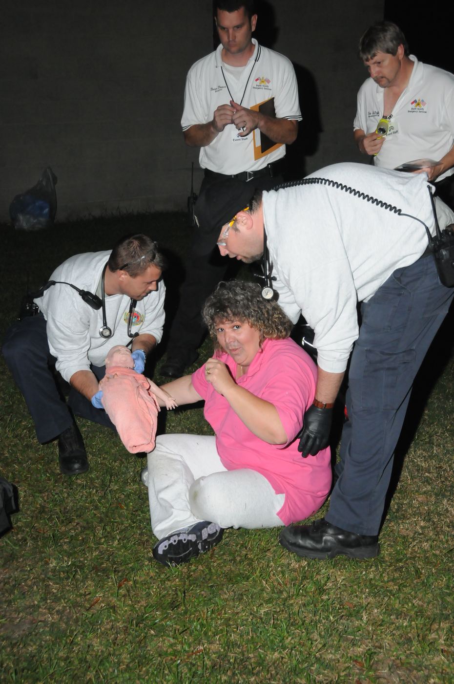 A team treating a seated patient holding an infant during a night scenario in Kenansville, 2009